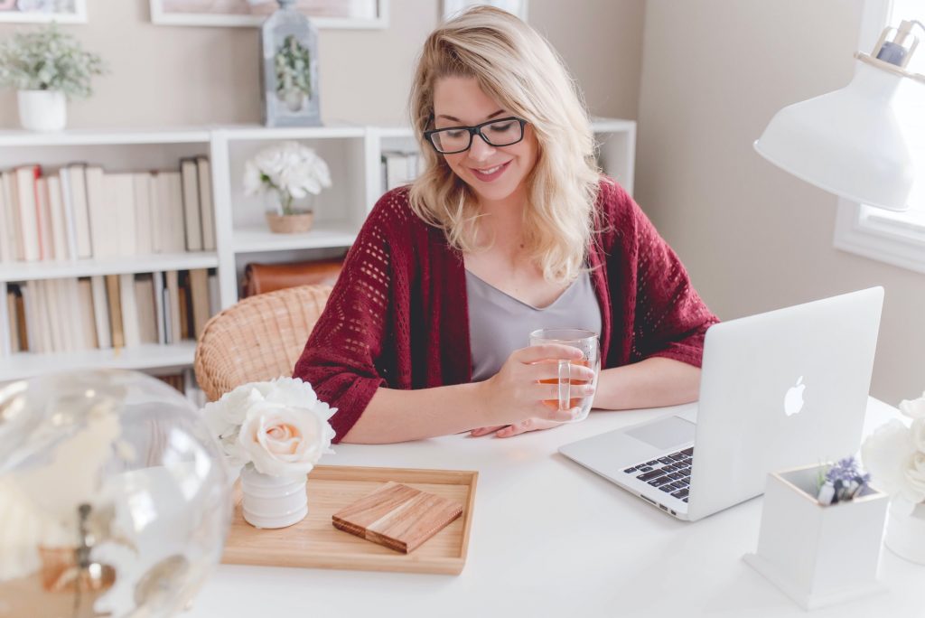 a woman sitting at a table with a laptop and a glass of water